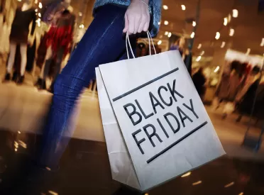 a woman holds a shopping bag at the mall that reads: "black Friday"