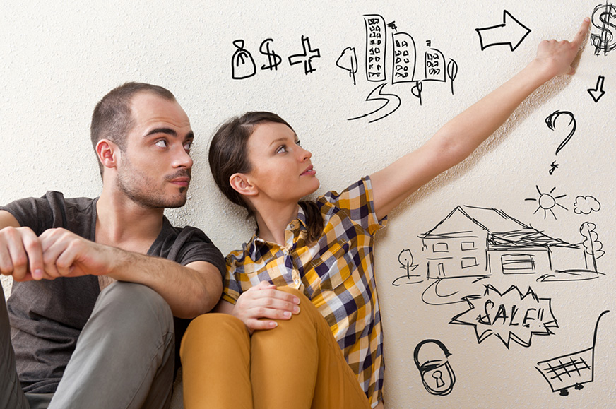 Couple sitting on the floor pointing to numbers on a whiteboard