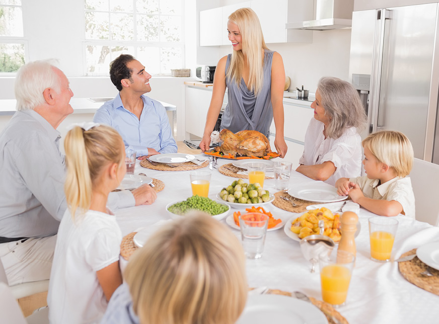 a family eating thanksgiving dinner sitting around a dining table