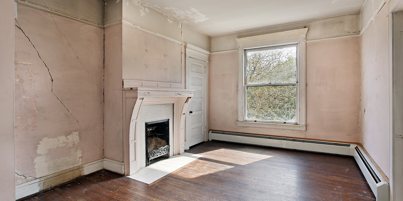 an empty living room with cracked walls