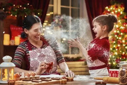 a mother and daughter are baking cookies at christmas and flour is flying in the air