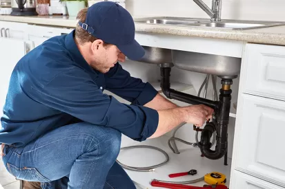 a man fixes pipes under a kitchen sink