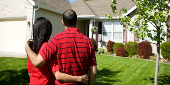 a couple embraces, looking at their home